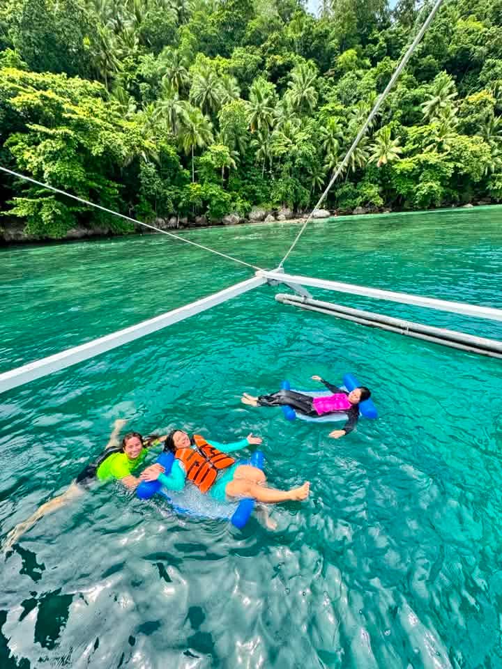Three guests floating and relaxing in emerald green water