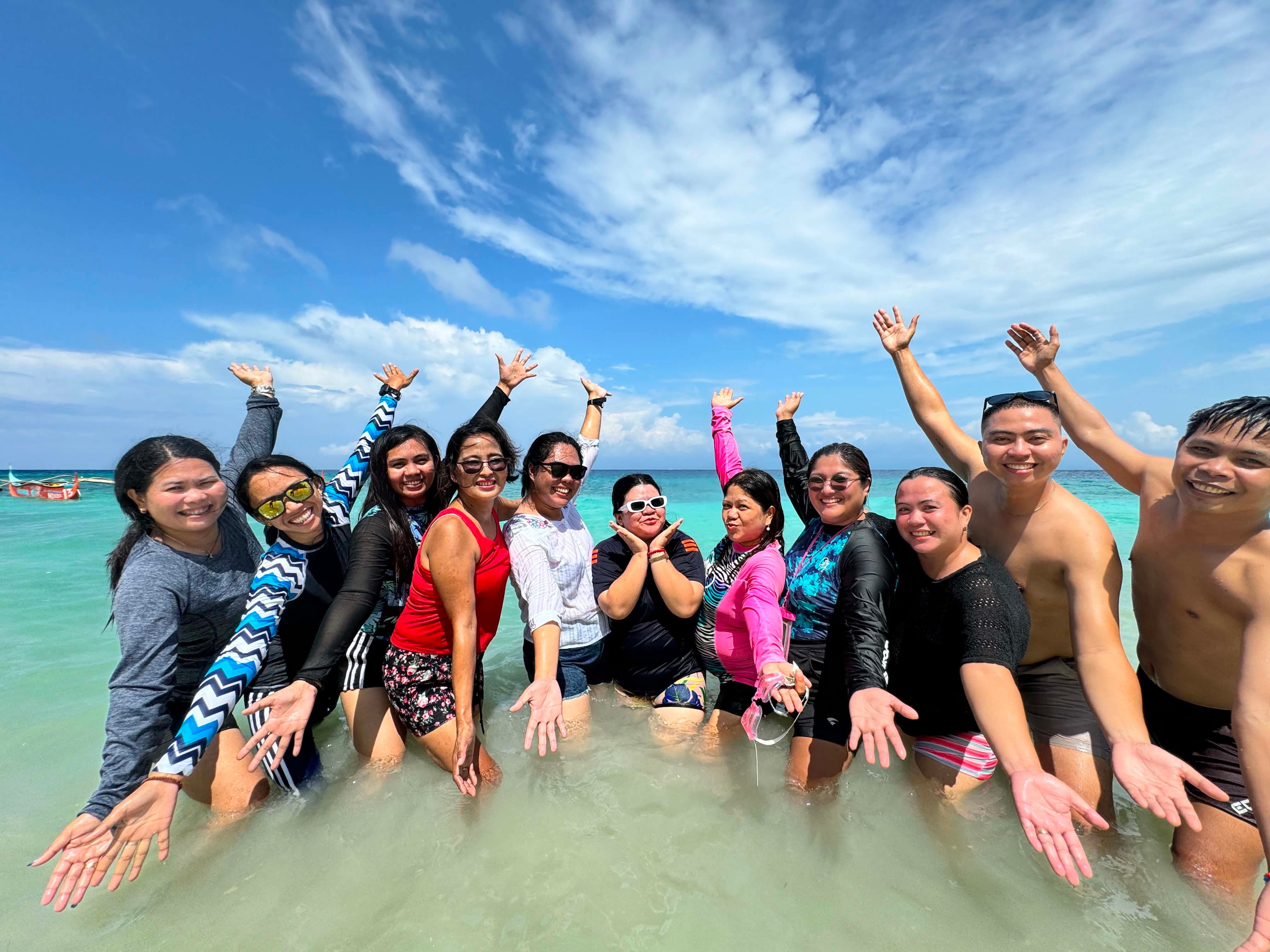 Group celebrating in turquoise water with hands raised in joy