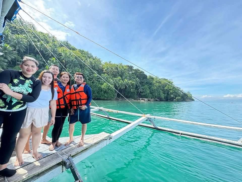 Small group of guests on boat outrigger with lush green island in the backdrop