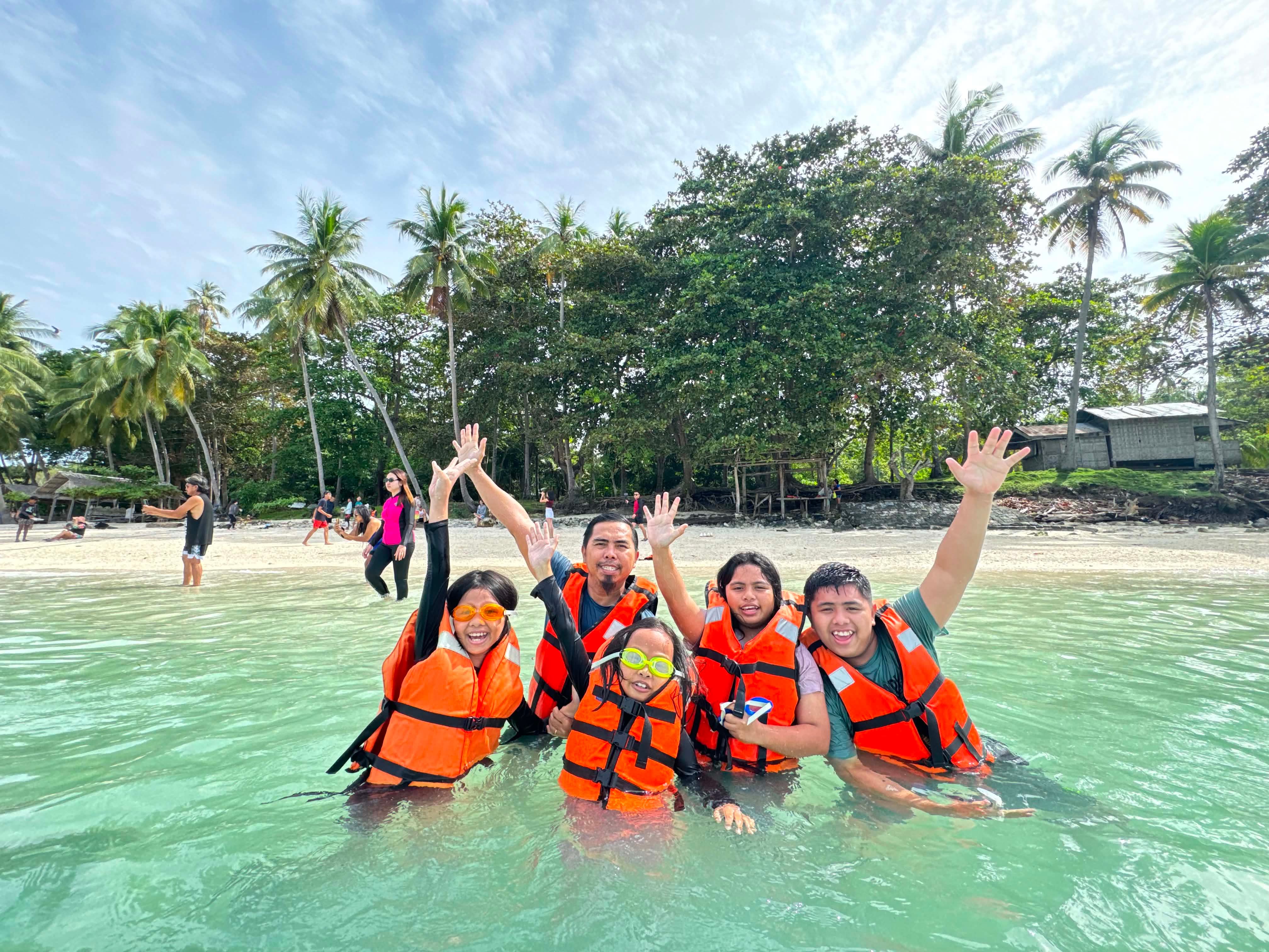 Family wearing orange life vests enjoying the ocean