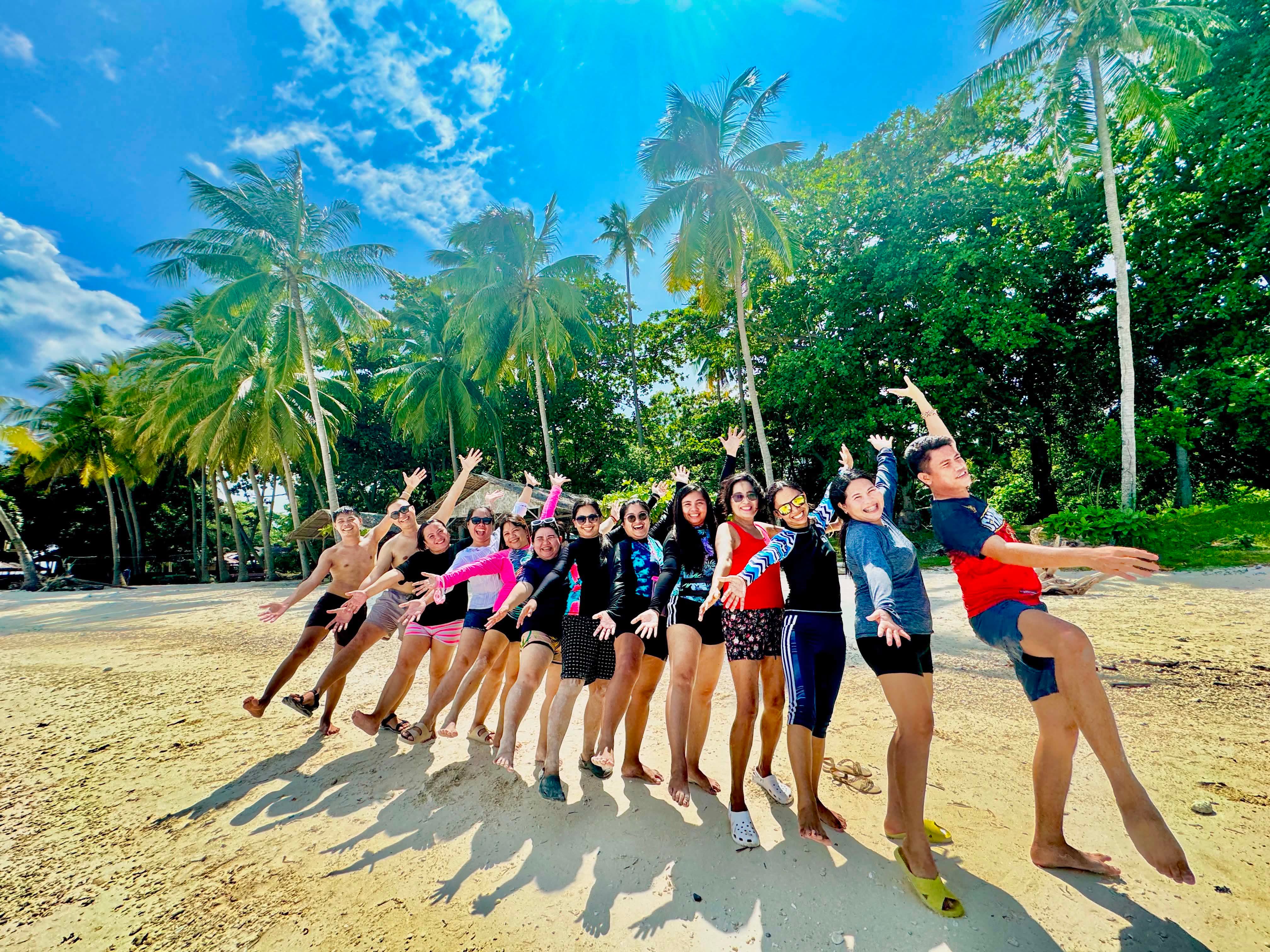 Group of guests posing on white sand beach